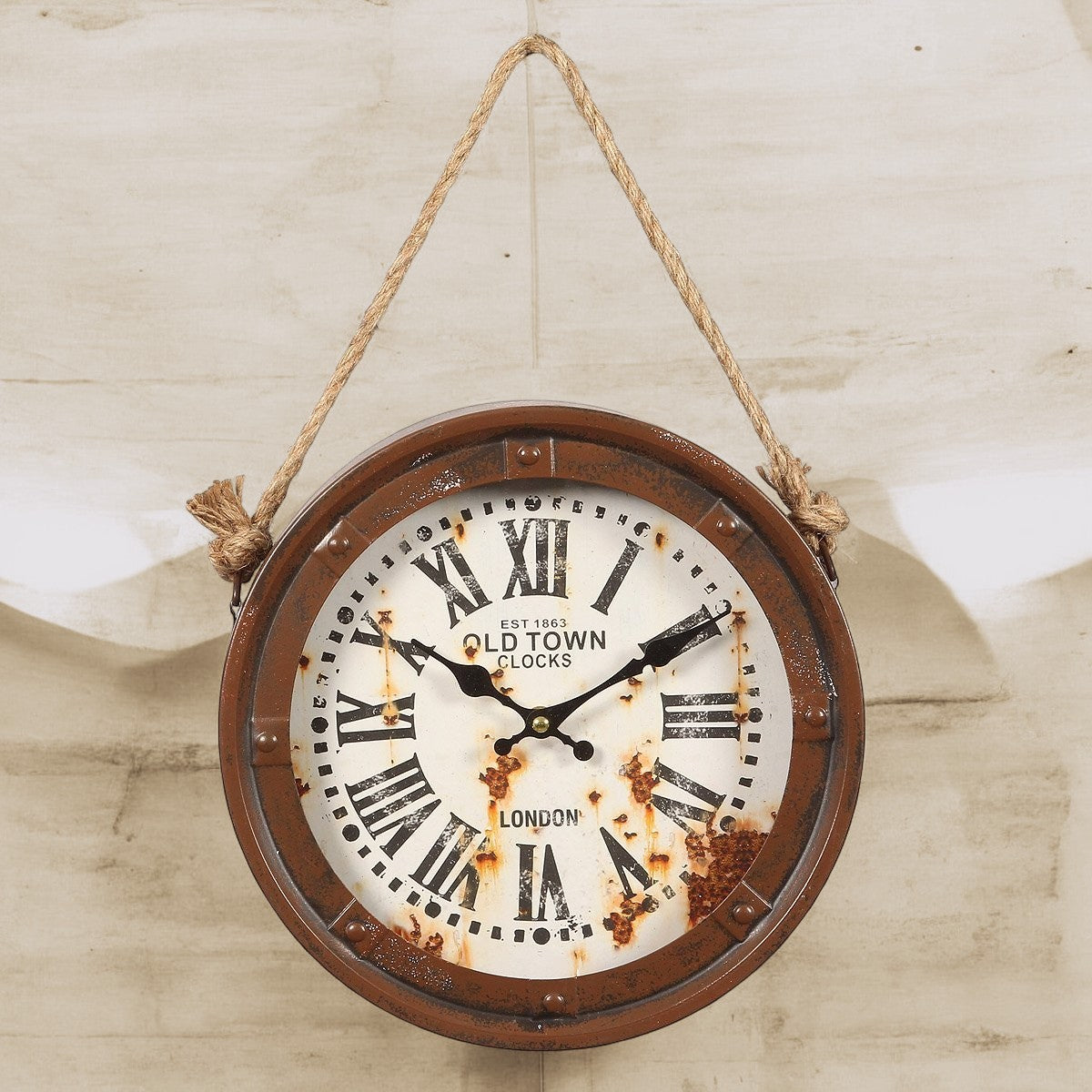 Une horloge ronde en metal rouillée suspendu par un corde de style vieux bâteau, sur un mur effet beton sépia chiffre romain. Inscription est 1863 old town clocks london s