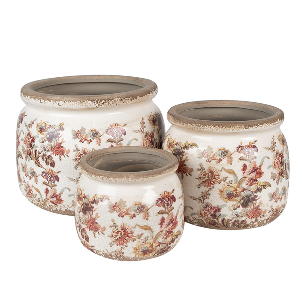 Un ensemble de trois pots de fleurs en céramique au style vintage, ornés d’un motif floral délicat dans des tons rouges, jaunes et verts sur un fond blanc vieilli. Chaque pot présente une finition patinée sur le bord supérieur, renforçant leur charme rustique et authentique. Disponibles en différentes tailles, ces pots apportent une touche d'élégance et de nostalgie à tout espace de décoration.